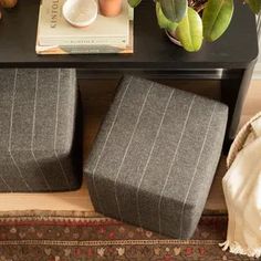 two gray stools sitting on top of a wooden table next to a book and plant