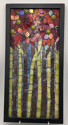 a piece of art that looks like stained glass with trees and flowers on the side