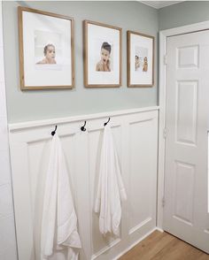 three pictures hang on the wall above two white towels hanging from hooks in front of a door