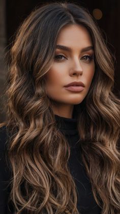 a woman with long, wavy hair and brown eyes is looking into the distance while wearing a black top