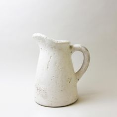 a white ceramic pitcher sitting on top of a table