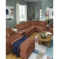 a living room filled with furniture and a large brown sectional couch sitting on top of a wooden floor