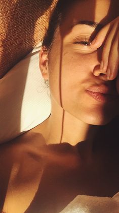 a woman laying on top of a bed next to a pillow with her eyes closed