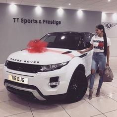 a woman standing next to a white range rover