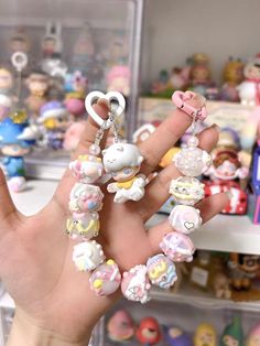 a hand holding several small charms in front of a shelf full of other toy figurines