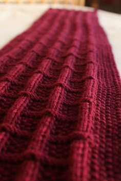 a red knitted blanket laying on top of a bed