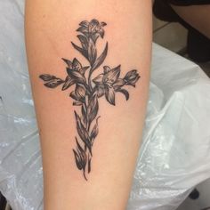 a cross tattoo with flowers on it