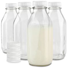 four glass bottles with milk in them on a white background