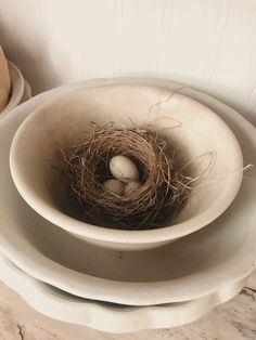 a bird's nest with two eggs in it on top of some plates and bowls