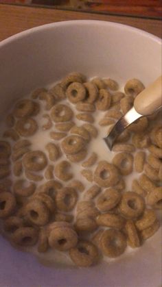 a bowl full of cereal with a spoon sticking out of the top and milk in it