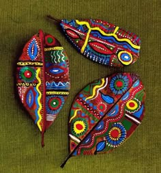 three colorfully painted leaf shaped objects on a green surface