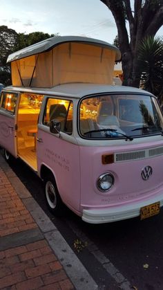 an old vw bus is parked on the side of the road with its doors open