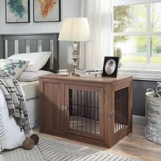 a dog crate in the middle of a bedroom with two pictures on the wall above it