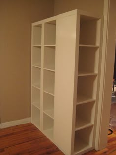 an empty room with white bookcases and hard wood floors