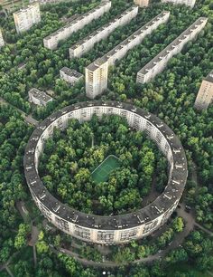 an aerial view of a circular building surrounded by lots of trees and buildings in the background