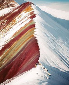 a mountain slope covered in snow and colored with red, orange, yellow and green