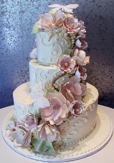 a three tiered wedding cake with flowers on top