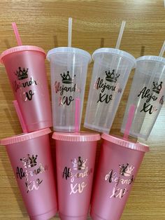 six plastic cups with straws in the shape of crowns and names on them, all lined up next to each other