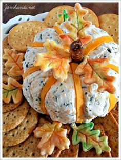 a cheese ball decorated with fall leaves on top of crackers