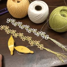 several different types of yarn and scissors on a wooden table next to balls of thread