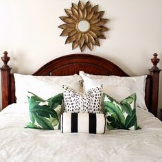 a bed with white sheets and black and white pillows on top of it next to a sunburst