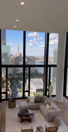 a living room filled with furniture and large windows overlooking a cityscape in the distance