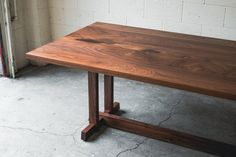 a wooden table sitting on top of a cement floor next to a brick wall and door