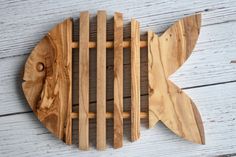 a fish shaped wooden cutting board sitting on top of a white wood floor next to a wall