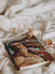 a book laying on top of a bed covered in white sheets and fallen leaves with the title mother's miss dears written above it