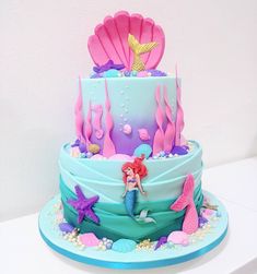 there is a cake decorated with mermaids and seashells