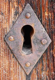 an old rusty door with a hole in the center and rivets on it