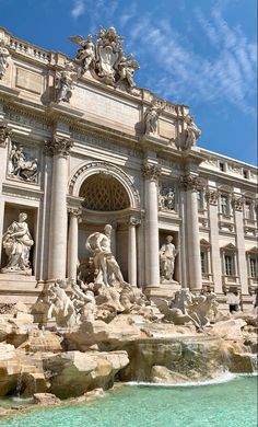 an ornate building with statues on the front and water running down it's sides