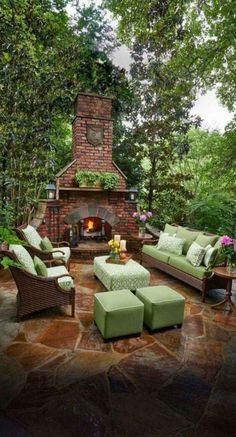 an outdoor living area with furniture and a fire place in the center, surrounded by trees