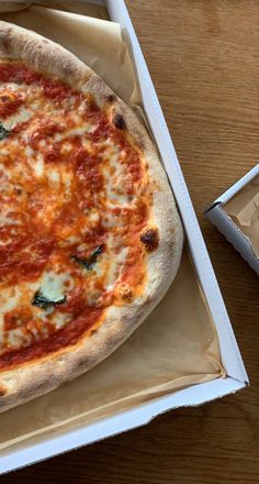 a pizza sitting in a box on top of a wooden table