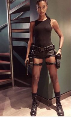 a woman in short shorts and boots standing next to a stair case with her hands on her hips