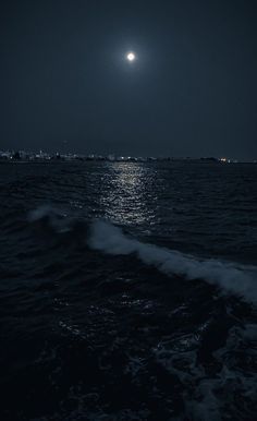 the moon is shining over the ocean at night