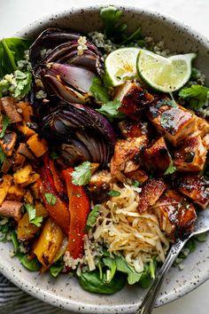 a bowl filled with meat, vegetables and rice next to a fork on top of a table