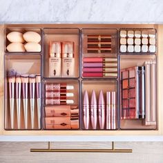 an organized makeup drawer with various cosmetics and other items in the drawers, including brushes