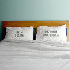 two pillows that have been placed on top of a bed with white sheets and pillow cases