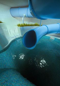 a water slide in the middle of a swimming pool with plants growing out of it