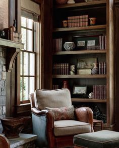 a living room filled with furniture and bookshelves next to a fire place in front of a window