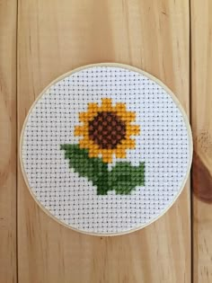 a cross stitch sunflower on a wooden table