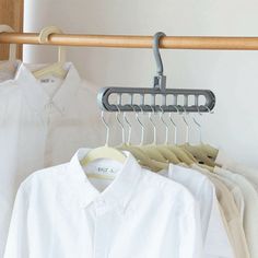 several white shirts are hanging on a rack in front of a wooden rail with clothes hangers