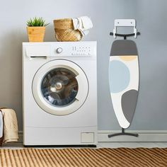 a washer sitting next to a dryer on top of a wooden floor in front of a gray wall