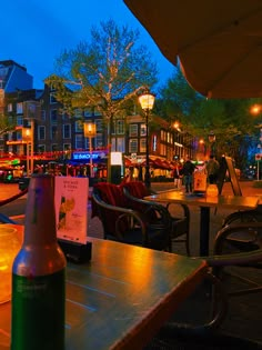 a bottle of beer sitting on top of a wooden table next to a lamp post