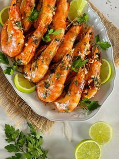 grilled shrimp on a plate with limes and parsley