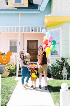 two women and a child holding balloons in front of a house with mickey mouse decorations