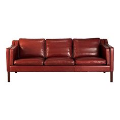 a red leather couch sitting on top of a white floor