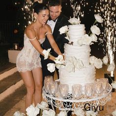 a man and woman cutting into a wedding cake with white flowers on the table in front of them