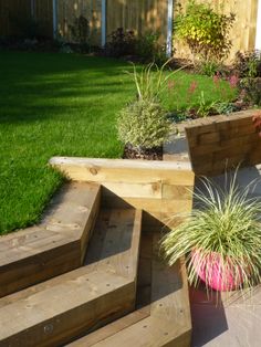 a wooden bench sitting on top of a lush green field next to a flower pot